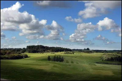 a view of a green golf course with clouds in the sky at Volstrup Ferieboliger in Stenild