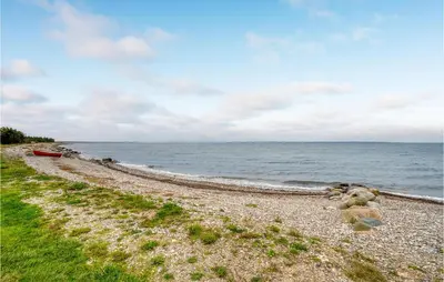 a rocky beach with a boat on the water at Holiday Home Hurup Thy Ij-1982 in Sønder Ydby
