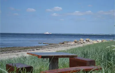 a picnic table and two chairs on the beach at Holiday Home Farsø Op-1966 in Farsø
