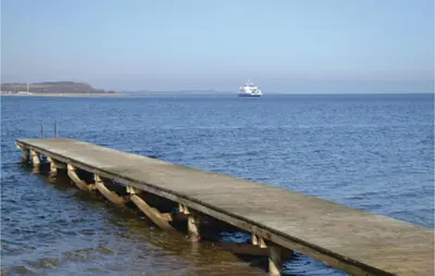 a pier in the ocean with a boat in the water at Holiday Home Farsø Qr-1965 in Farsø