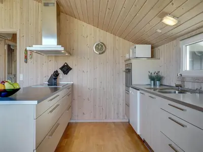 a kitchen with white appliances and a wooden ceiling at Holiday Home Emelia - 50m from the sea by Interhome in Torsted