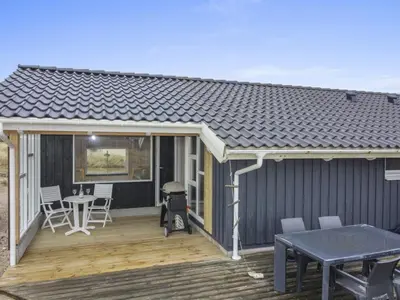 a house with a deck with a grill and a table at Holiday Home Emelia - 50m from the sea by Interhome in Torsted