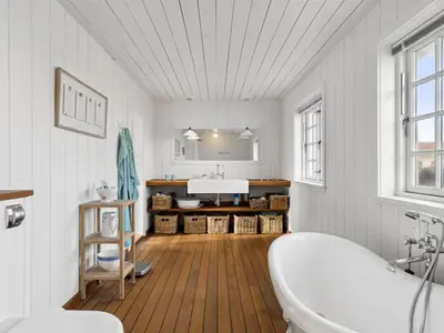 a white bathroom with a tub and a sink at Holiday Home Jeppe - 200m from the sea by Interhome in Blokhus