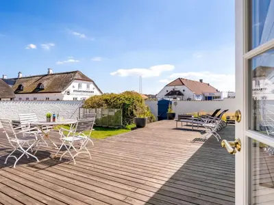 a deck with tables and chairs on a house at Holiday Home Jeppe - 200m from the sea by Interhome in Blokhus
