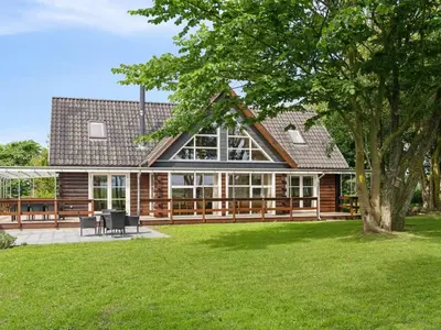 a log home with a patio and a tree at Holiday Home Månviva - 150m to the fjord by Interhome in Redsted