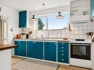 a kitchen with blue cabinets and a window at Holiday Home Birtir - 750m from the sea by Interhome in Hanstholm