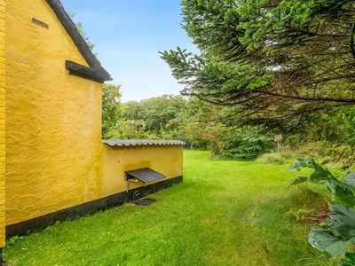 a bench in a yard next to a yellow building at Holiday Home Birtir - 750m from the sea by Interhome in Hanstholm