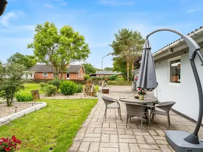 a patio with a table and chairs and an umbrella at Holiday Home Elara - 300m from the sea by Interhome in Thyholm