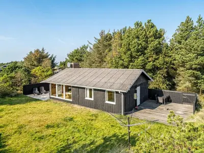 a small black house with a wooden deck at Holiday Home Swenki - 700m from the sea by Interhome in Saltum