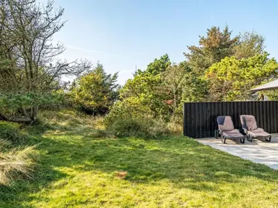 a patio with two chairs and a lawn at Holiday Home Swenki - 700m from the sea by Interhome in Saltum