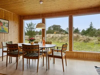 a dining room with a table and chairs and a large window at Holiday Home Swenki - 700m from the sea by Interhome in Saltum