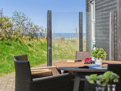 a table and chairs on a patio with a view of the ocean at Holiday Home Ajvi - 900m from the sea by Interhome in Blokhus