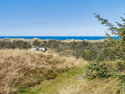 a trail through the hills with a house in the distance at Holiday Home Ajvi - 900m from the sea by Interhome in Blokhus