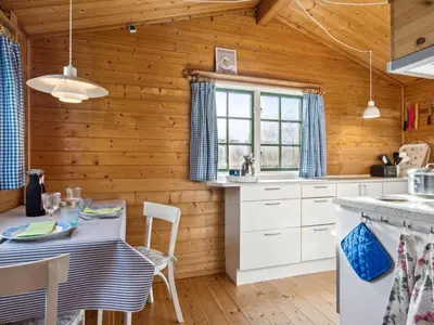 a kitchen with wooden walls and a table and chairs at Holiday Home Bonde - 800m to the fjord by Interhome in Farsø