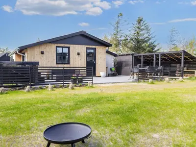 a house with a black table in the grass at 4 star holiday home in Løgstør-By Traum in Løgsted
