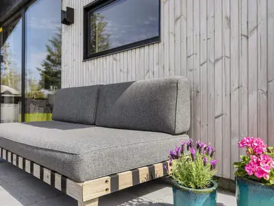 a couch sitting on a patio with some flowers at 4 star holiday home in Løgstør-By Traum in Løgsted