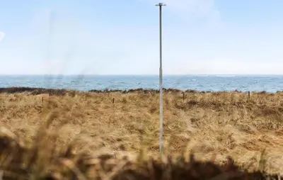 a pole in the middle of a field with the ocean at 3 Bedroom Pet Friendly Home In Frøstrup in Frøstrup
