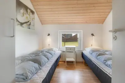two beds in a room with a window at Cozy holiday house with pool by the sea - SJ940 in Harboør