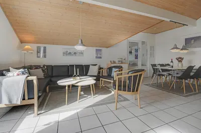 a living room with a couch and a table and chairs at Cozy holiday house with pool by the sea - SJ940 in Harboør