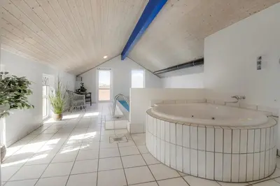 a large bathroom with a tub in the middle of the room at Cozy holiday house with pool by the sea - SJ940 in Harboør