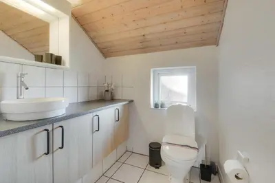 a white bathroom with a toilet and a sink at Cozy holiday house with pool by the sea - SJ940 in Harboør