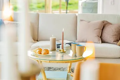 a living room with a table with candles and a couch at Uniquely located wooden cottage by the sea - SJ1 in Harboør