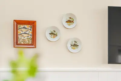 three plates on a wall with a picture on it at Uniquely located wooden cottage by the sea - SJ1 in Harboør