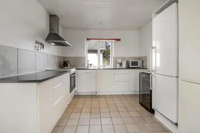 a white kitchen with white cabinets and appliances at Pool house with beautiful view by the sea - SJ650 in Lemvig