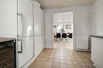 a kitchen with white cabinets and a tile floor at Pool house with beautiful view by the sea - SJ650 in Lemvig
