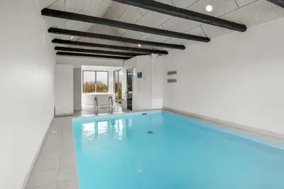 a swimming pool in a building with blue lighting at Pool house with beautiful view by the sea - SJ650 in Lemvig