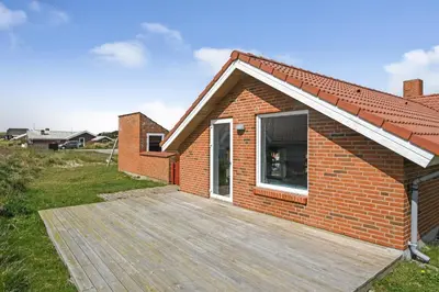a brick house with a wooden deck in front of it at Holiday home with spa and pool by the sea - SJ670 in Harboør