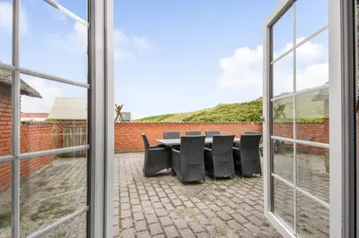 a window view of a patio with a table and chairs at Thatched house with spa and pool by the sea - SJ67 in Harboør