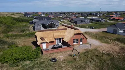 an aerial view of a house with a roof at Thatched house with spa and pool by the sea - SJ67 in Harboør