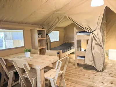 a dining room with a table and a bed in a tent at Himmerland camping & Feriecenter in Års