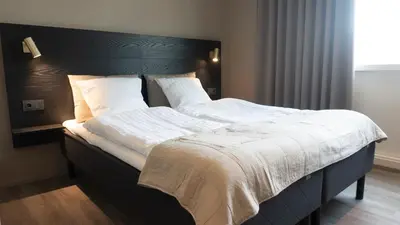 a bedroom with a large bed with a black headboard at Hotel Nørreport in Holstebro