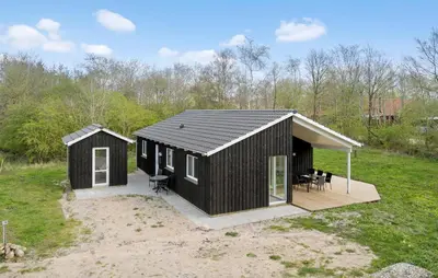 a black cabin in a field with a patio at 4 Bedroom Nice Home In Vinderup in Vinderup