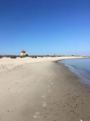 a sandy beach with a lighthouse in the distance at Nyd den skønne natur ved hav og fjord in Thyborøn