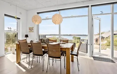 a dining room with a table and chairs and large windows at Stunning Home In Roslev With Kitchen in Roslev