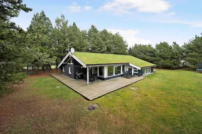 a house with a green roof on a field at Pool summerhouse in Saltum near Blokhus in Saltum