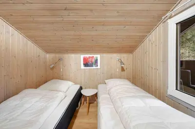 two beds in a small room with a window at Pool summerhouse in Saltum near Blokhus in Saltum