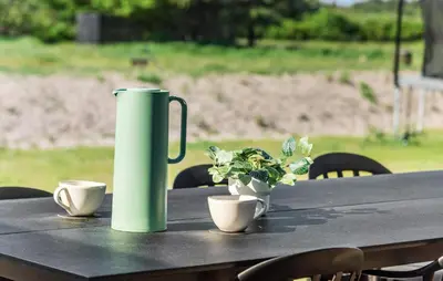 a green watering can sitting on a table with plants at Stunning Home In Saltum With Sauna in Saltum