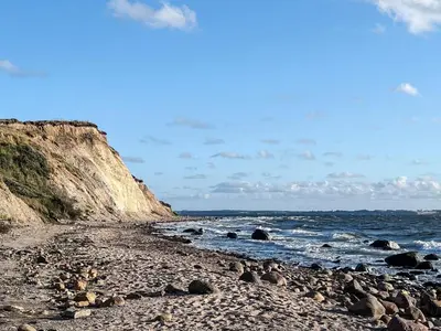 a beach with rocks and the ocean on a sunny day at 6 person holiday home in Farsø-By Traum in Farsø