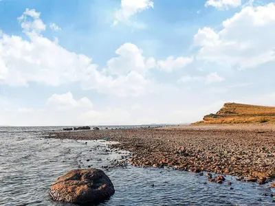 a beach with a large rock in the water at 6 person holiday home in Farsø-By Traum in Farsø