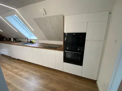 a kitchen with white cabinets and a black microwave at Sunny apartment in Åbybro