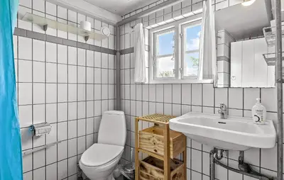 a white bathroom with a toilet and a sink at 4 Bedroom Nice Home In Blokhus in Blokhus