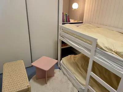 a small room with a bunk bed and a stool at Dejligt sommerhus med udsigt over fjorden in Løgstrup