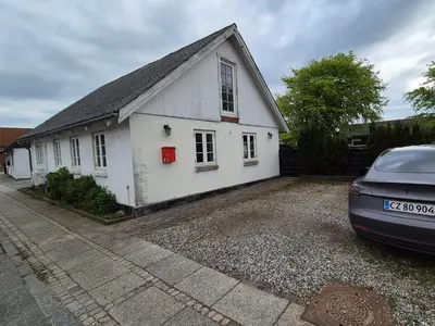 a white house with a car parked in front of it at Marku House in Struer