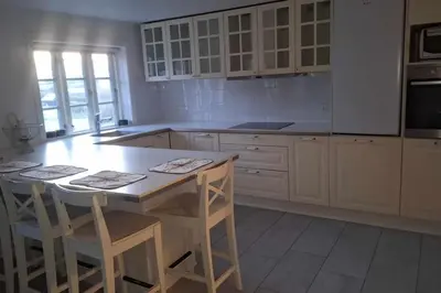 a kitchen with white cabinets and a table with stools at Marku House in Struer