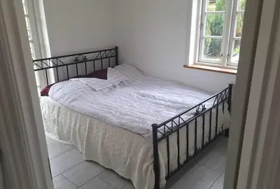 a bed in a white bedroom with a window at Marku House in Struer