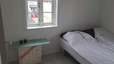 a bedroom with a bed and a table next to a window at Marku House in Struer